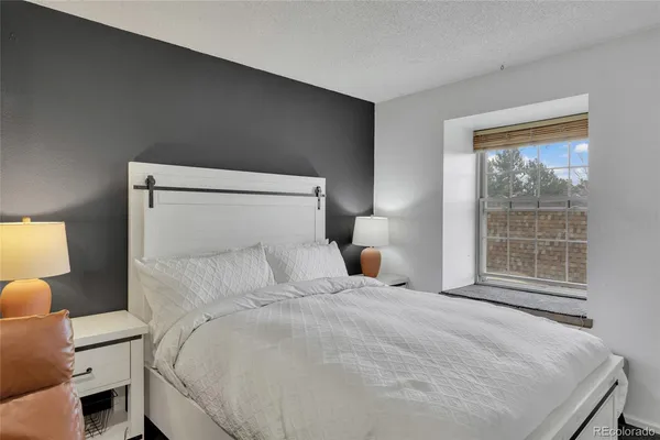 a bedroom with a bed and a lamp next to a window