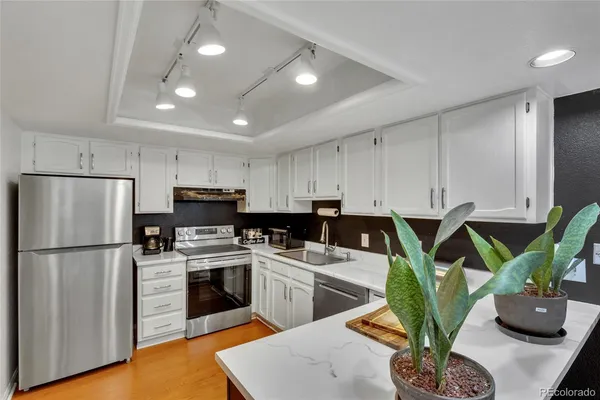 a kitchen with sink a refrigerator and white cabinets