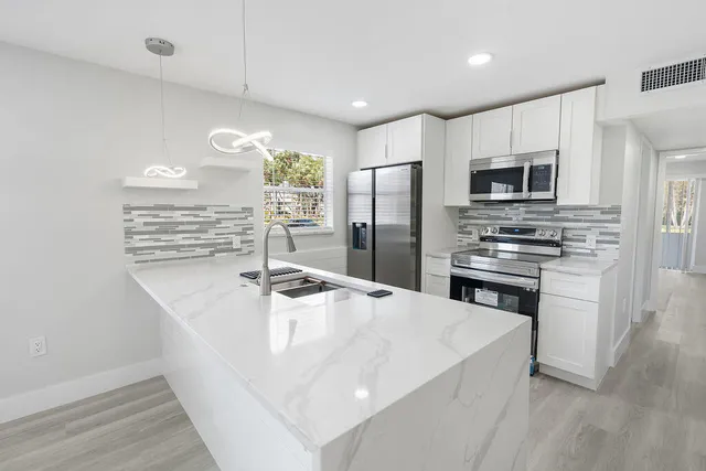 a kitchen with kitchen island a sink appliances and cabinets