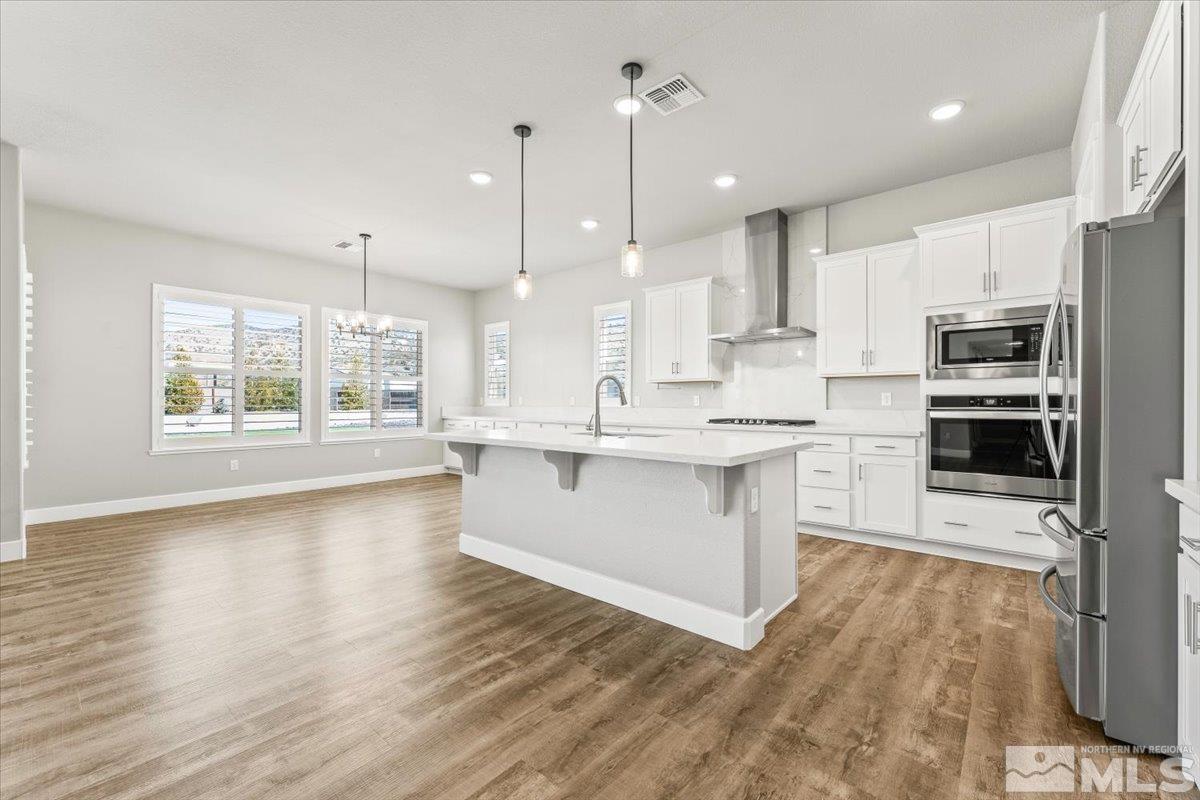 1273 Crawford Crk Drive Reno, NV 89521 - Photo 8 of 39 a large kitchen with stainless steel appliances kitchen island granite countertop a stove a sink a refrigerator a center island and wooden floor