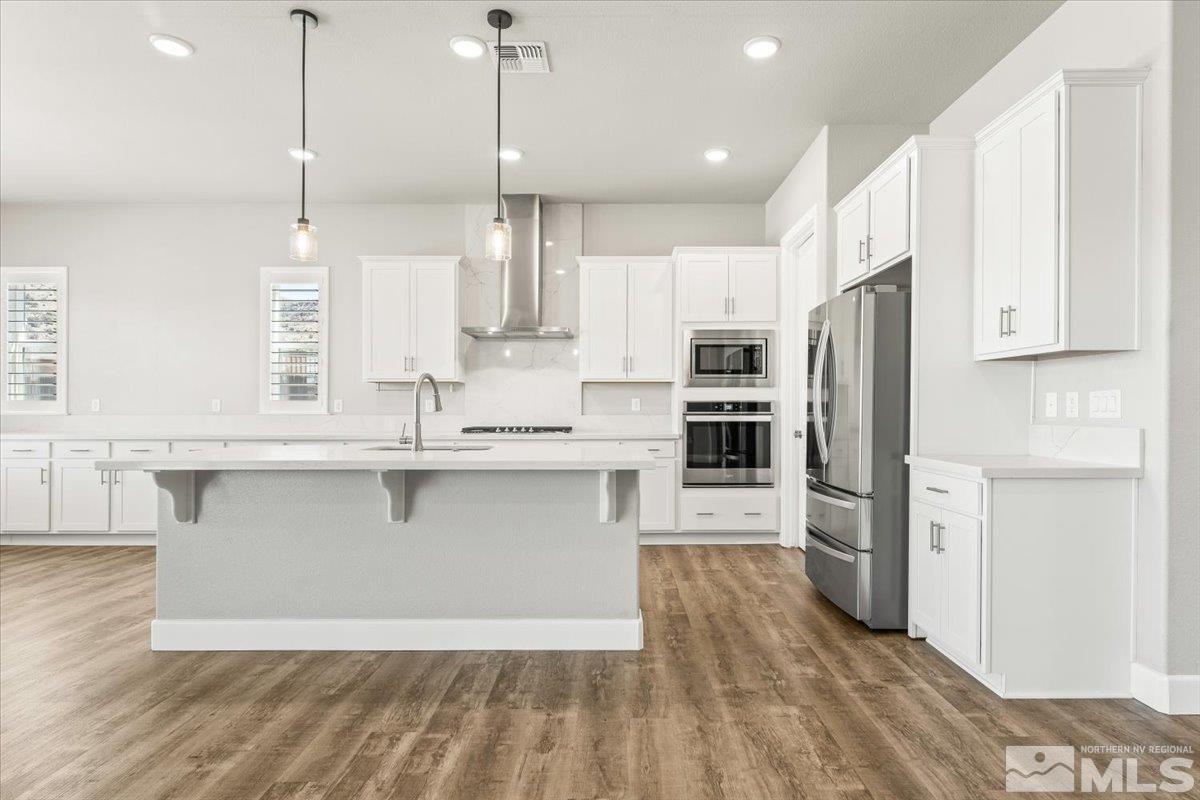 1273 Crawford Crk Drive Reno, NV 89521 - Photo 9 of 39 a kitchen with stainless steel appliances granite countertop a refrigerator a sink a stove and white cabinets with wooden floor