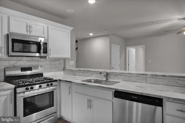 a kitchen with granite countertop a stove a microwave a sink and cabinets