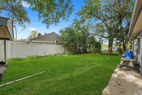 a view of a backyard with potted plants and large trees