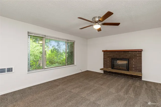 a view of empty room with fireplace and windows