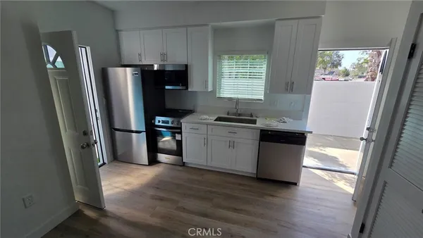 a kitchen with stainless steel appliances a refrigerator sink and wooden floor