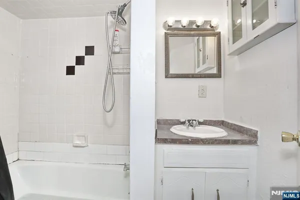 a bathroom with a granite countertop sink a mirror and a shower