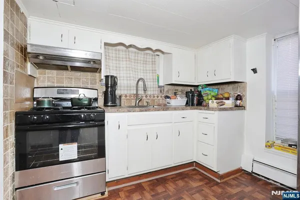 a kitchen with stainless steel appliances granite countertop a stove and white cabinets
