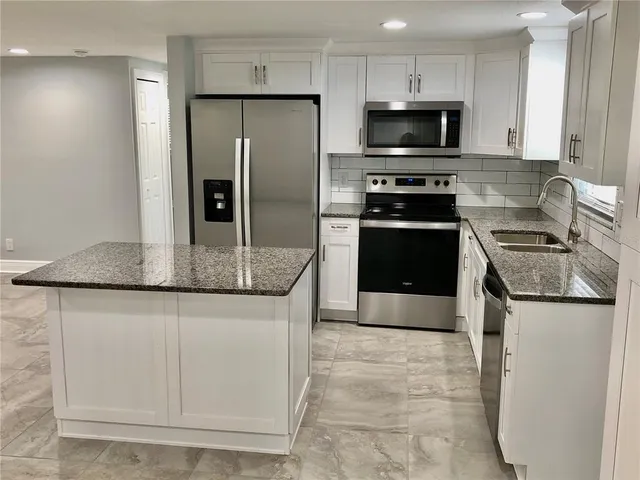 a kitchen with granite countertop a refrigerator and a stove top oven