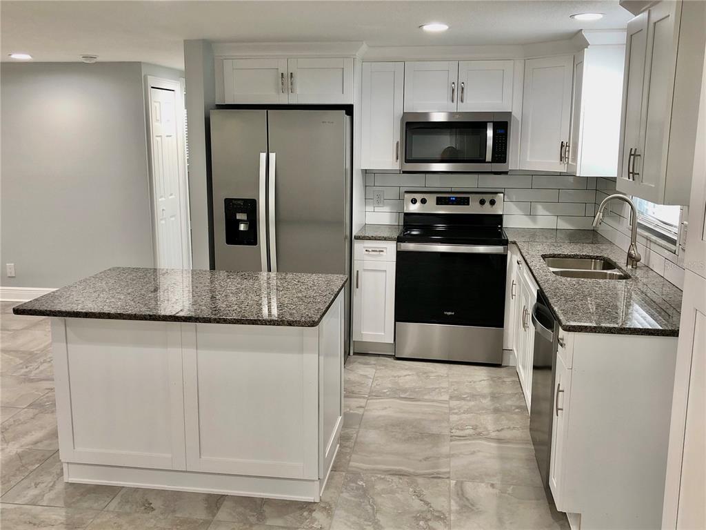 11001 Riverview Drive Riverview, FL 33578 - Photo 3 of 8 a kitchen with granite countertop a refrigerator and a stove top oven