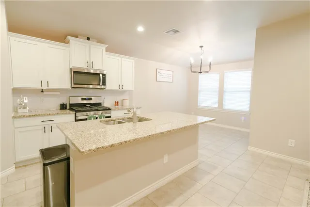 a kitchen with kitchen island granite countertop a sink appliances cabinets and a counter top space