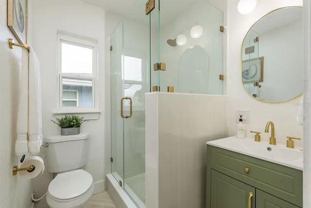 a bathroom with a toilet a sink a mirror a vanity and shower