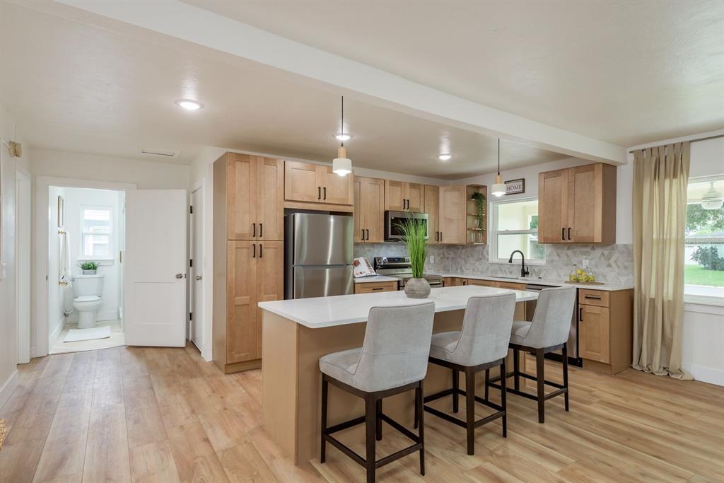 1448 Lemon Street Clearwater, FL 33756 - Photo 8 of 33 a kitchen with stainless steel appliances a dining table chairs refrigerator and cabinets