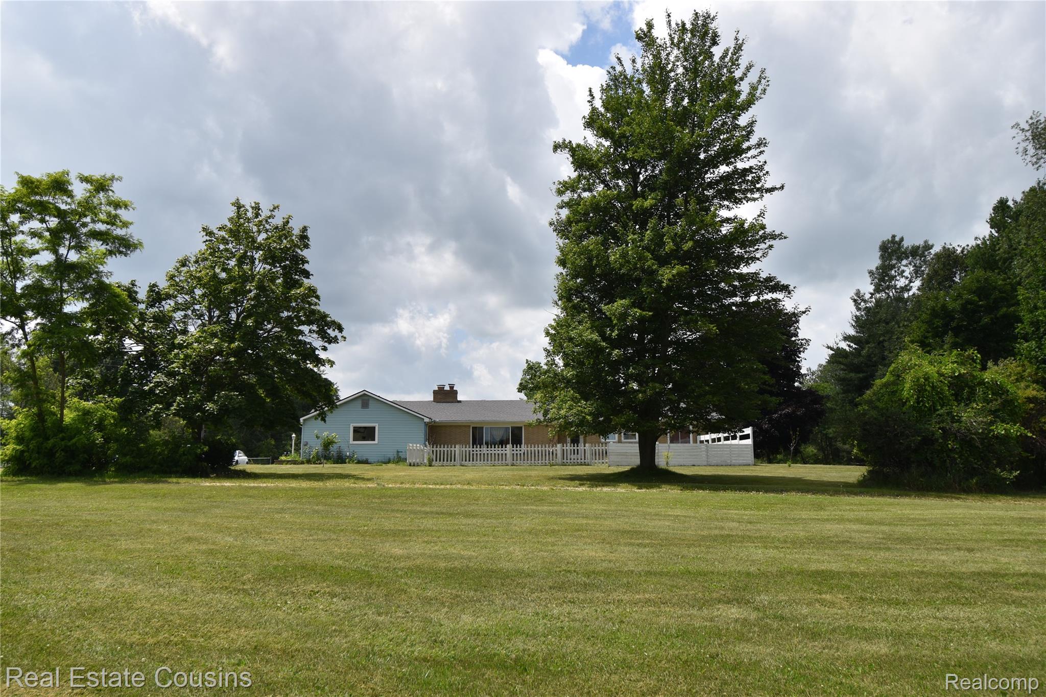 2247 Johnson Mill Road North Branch, MI 48461 - Photo 7 of 22 Expansive green lawn bordering a light blue and beige single-story residence