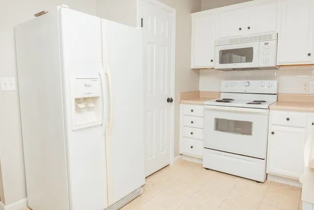 a kitchen with white cabinets and white appliances