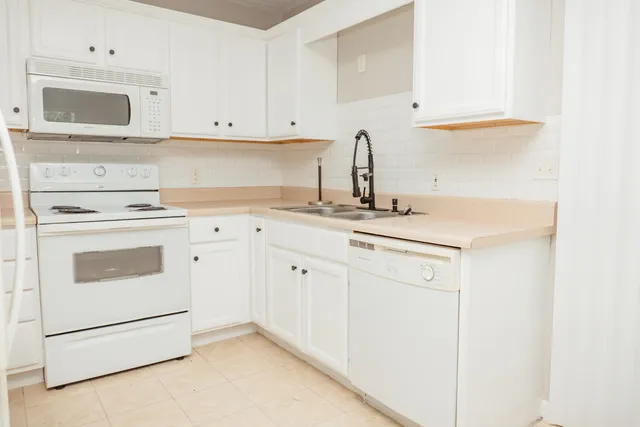 a kitchen with white cabinets and white appliances