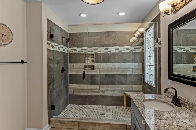 a bathroom with a granite countertop sink a mirror and shower