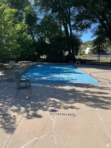1175 Canyon Road, Unit A 5 Ogden, UT 84404 - Photo 5 of 15 Outdoor pool area featuring a blue pool cover, surrounding concrete deck, and mature trees providing shade