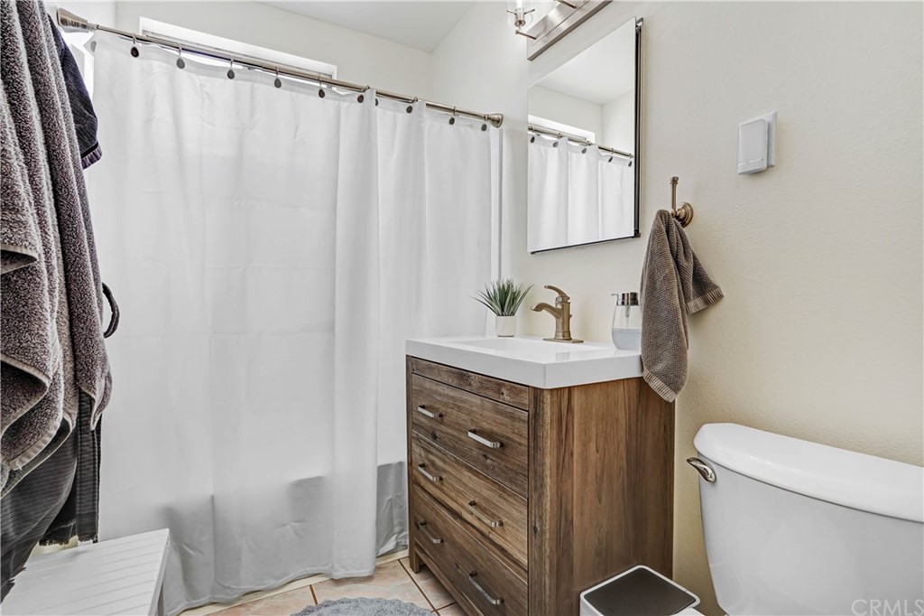 10223 25th Street Rancho Cucamonga, CA 91730 - Photo 16 of 17 a bathroom with a sink a toilet and shower curtain