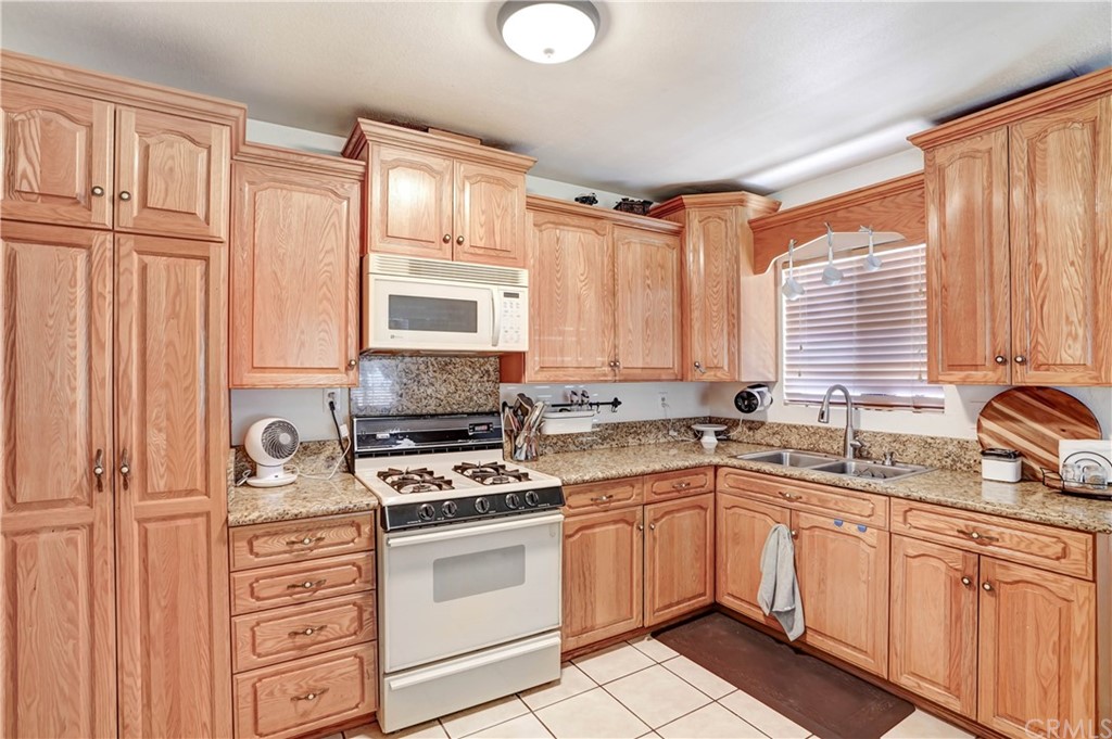 10223 25th Street Rancho Cucamonga, CA 91730 - Photo 9 of 17 a kitchen with granite countertop a sink cabinets stainless steel appliances and a window