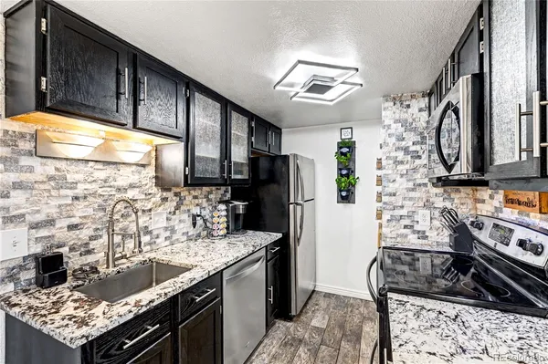 a kitchen with stainless steel appliances kitchen island granite countertop a stove refrigerator and microwave