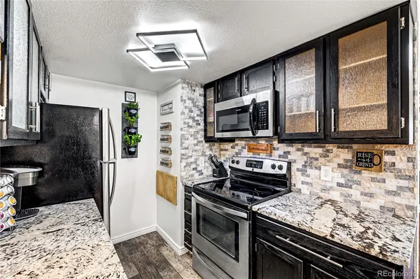 a kitchen with stainless steel appliances granite countertop a stove a sink and a microwave