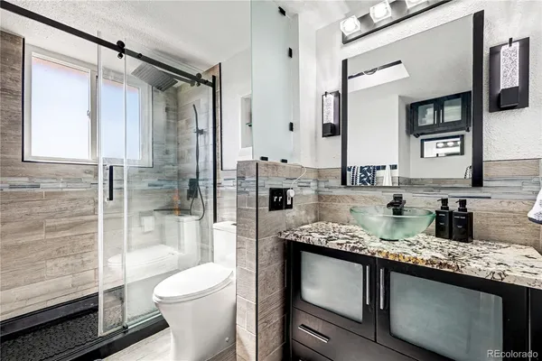 a bathroom with a granite countertop sink toilet and shower