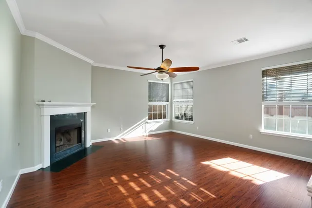 a view of empty room with wooden floor fireplace and window