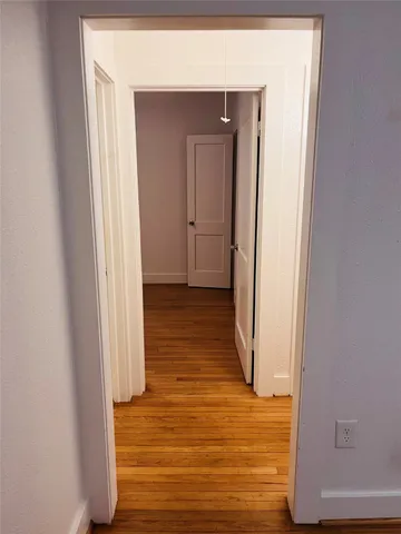 a view of a hallway with wooden floor and staircase