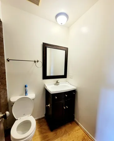 a bathroom with a toilet sink vanity granite and mirror