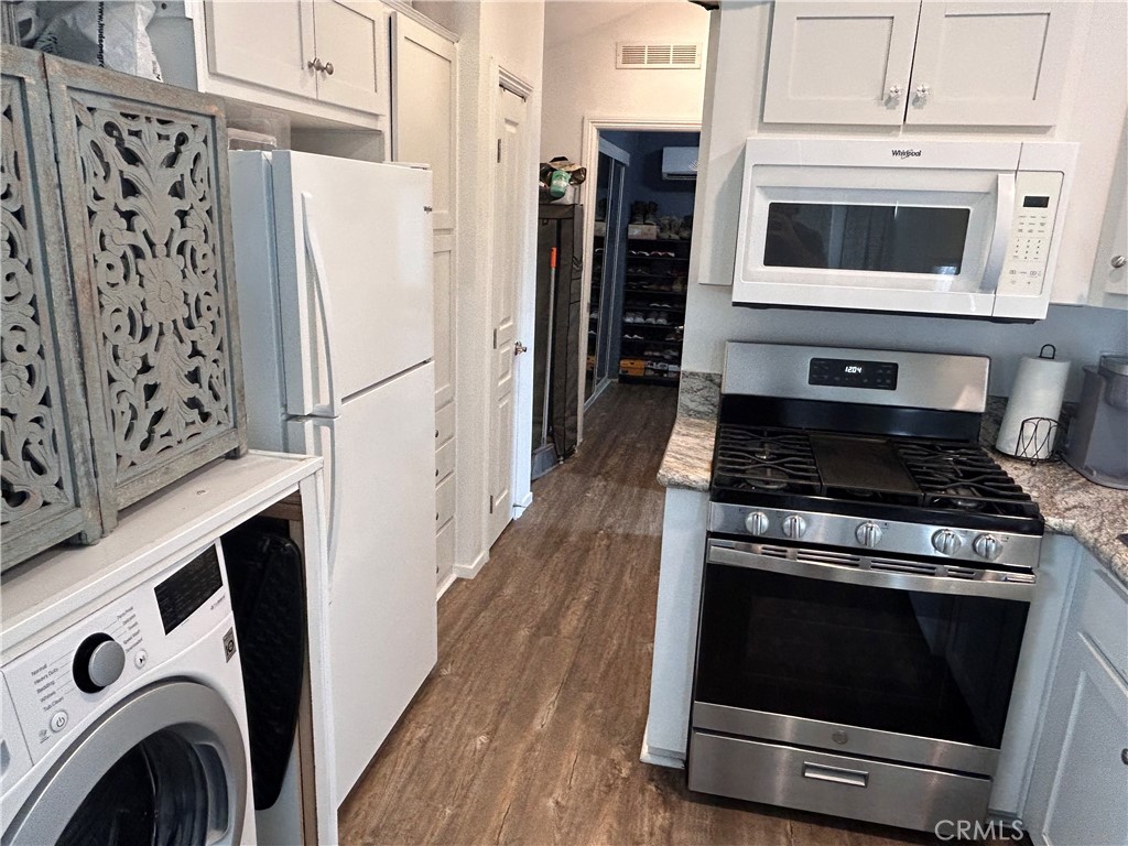 1409 Redlands Boulevard, Unit 27 Redlands, CA 92373 - Photo 11 of 15 a kitchen with granite countertop a stove and a microwave with wooden floor