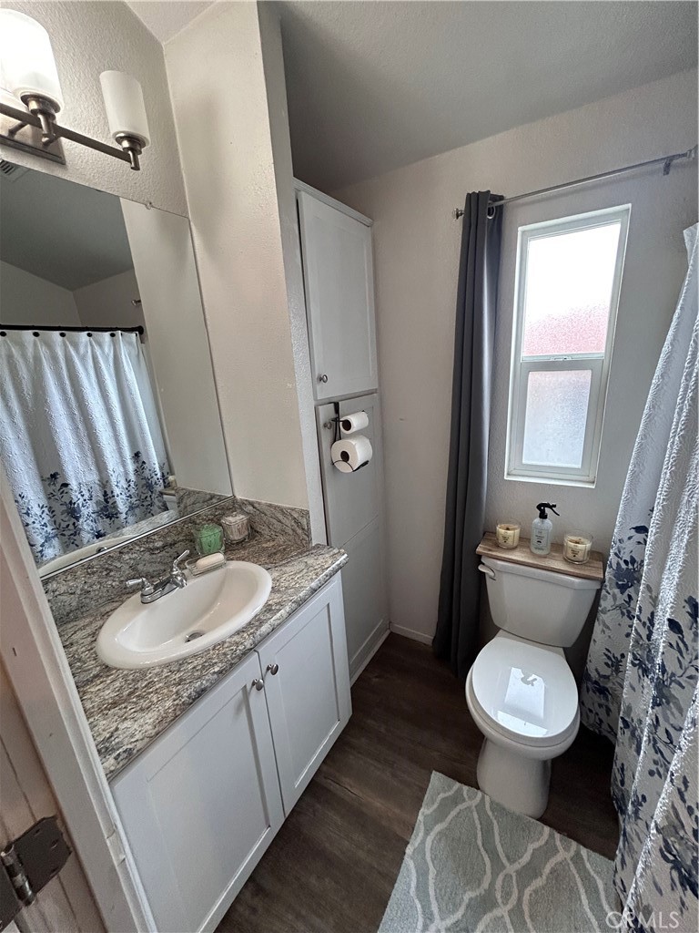 1409 Redlands Boulevard, Unit 27 Redlands, CA 92373 - Photo 13 of 15 a bathroom with a granite countertop toilet a sink and a mirror