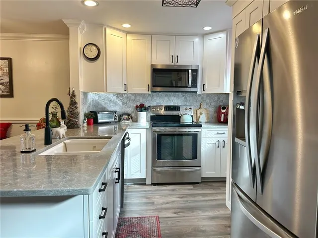 a kitchen with stainless steel appliances granite countertop a sink a stove a refrigerator and cabinets