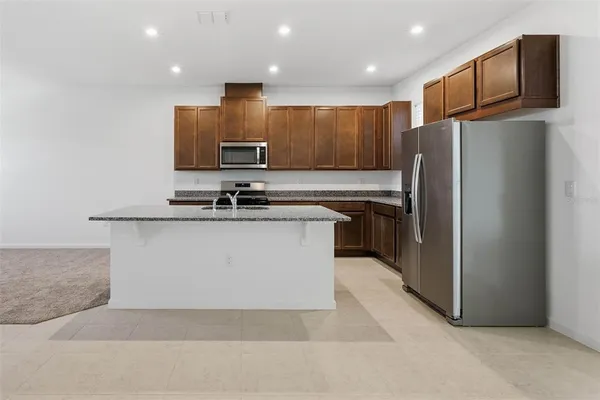 a view of kitchen with stainless steel appliances granite countertop refrigerator stove microwave and oven