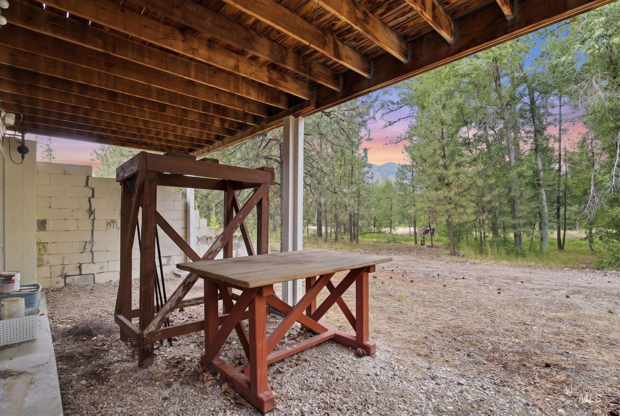 3980 North Pine-Featherville Road Mountain Home, ID 83647 - Photo 9 of 35 Covered outdoor area with exposed wood beam ceiling, gravel ground cover, and a concrete block wall