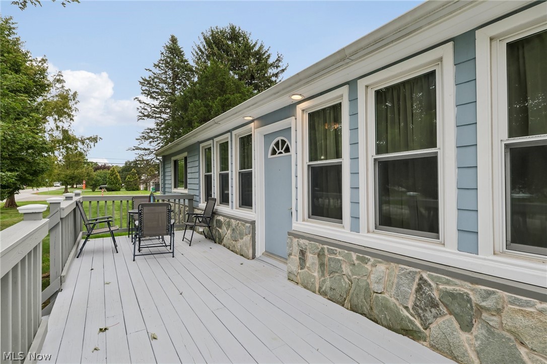 4188 Manchester Road Perry, OH 44081 - Photo 4 of 41 Expansive exterior decking with painted wood railings, a light blue siding facade, stone foundation accents, and multiple windows