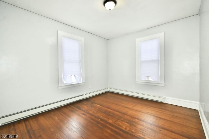 519 Clinton Place, Unit 2R Newark, NJ 07112 - Photo 5 of 14 an empty room with wooden floor and windows