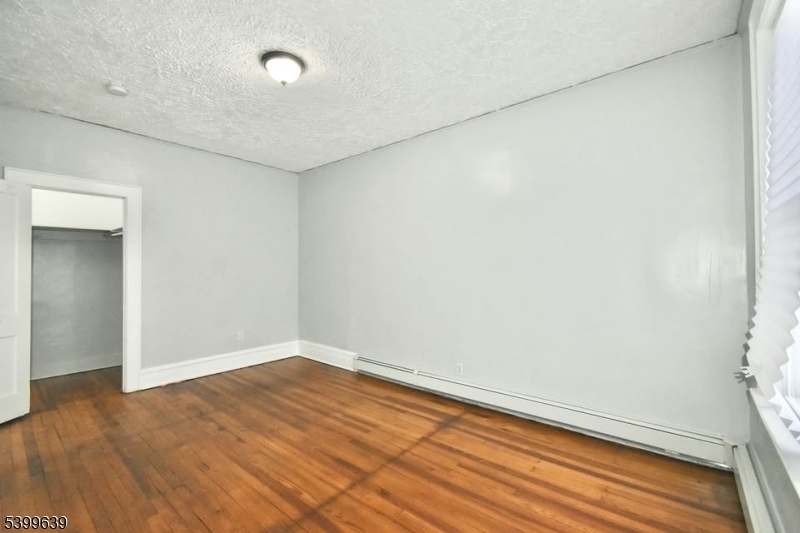 519 Clinton Place, Unit 2R Newark, NJ 07112 - Photo 6 of 14 an empty room with wooden floor and windows