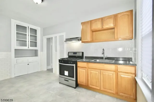 a kitchen with granite countertop a stove a sink and a microwave