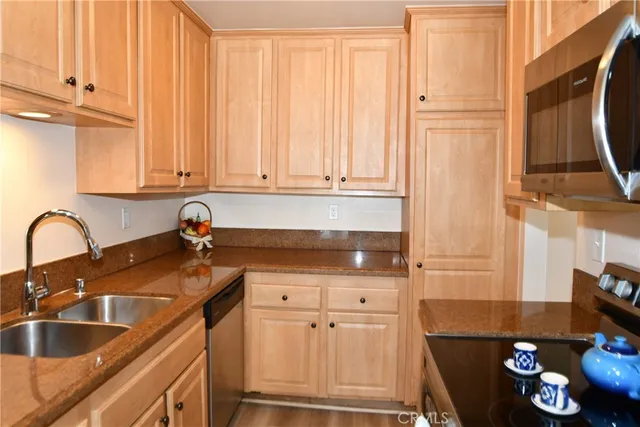 a kitchen with granite countertop a sink stainless steel appliances and cabinets