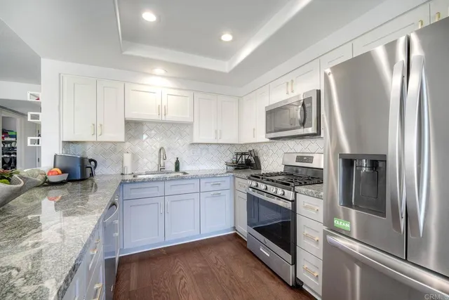 a kitchen with stainless steel appliances granite countertop a stove top oven a sink and a refrigerator