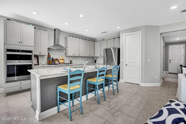 a living room with stainless steel appliances kitchen island granite countertop a table chairs sink and cabinets