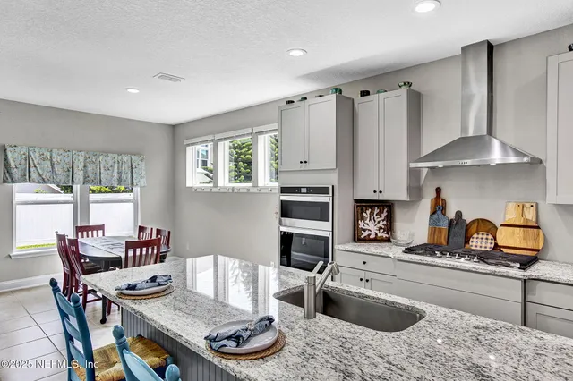 a kitchen with granite countertop a stove a sink a dining table and chairs