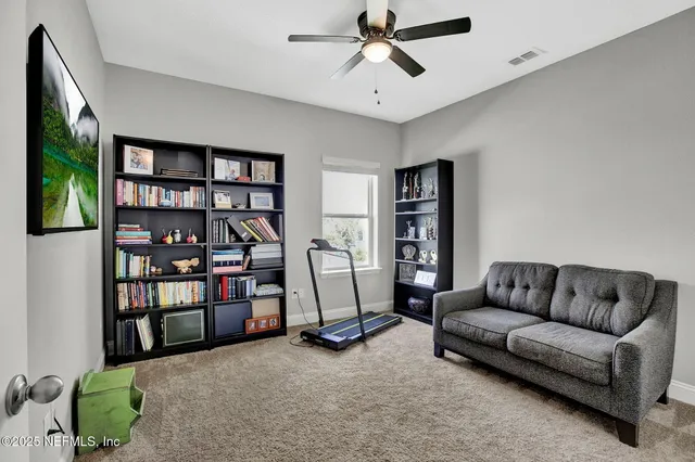 a living room with furniture a ceiling fan and a book shelf
