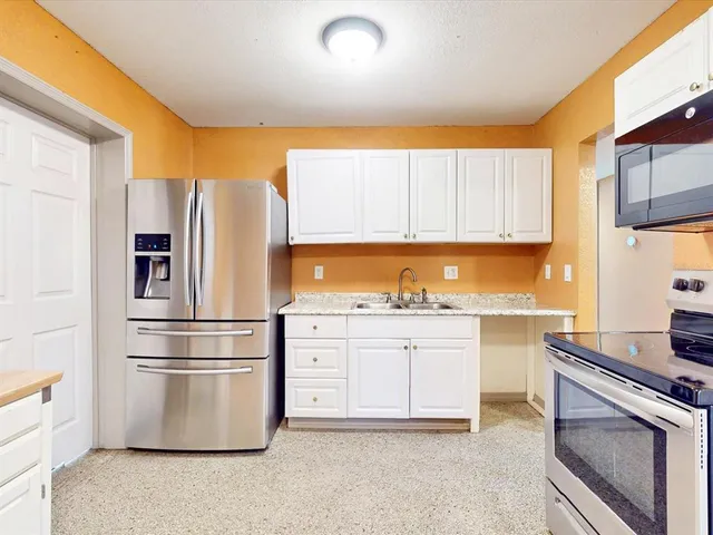 a kitchen with stainless steel appliances granite countertop a refrigerator sink and stove