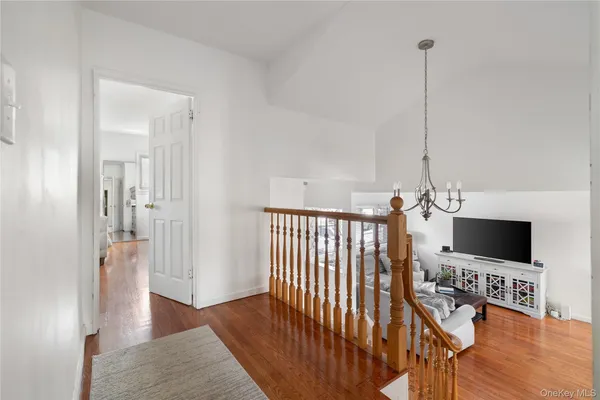 a view of a hallway with wooden floor windows and a chandelier