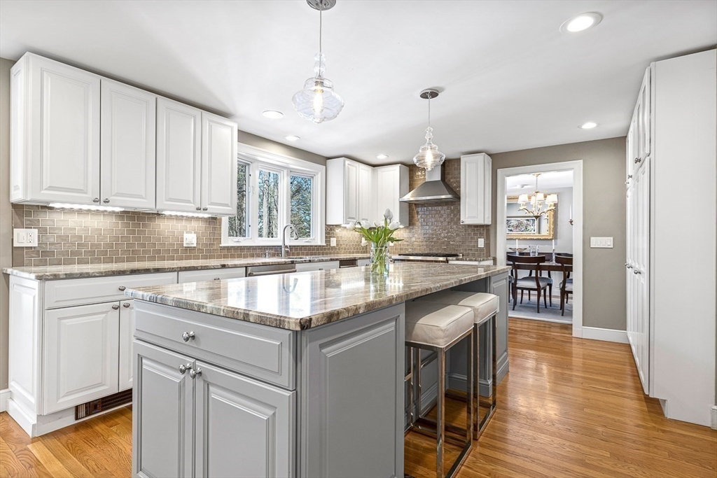 359 Grove Street Needham, MA 02492 - Photo 8 of 37 a kitchen with kitchen island granite countertop wooden floors and white cabinets