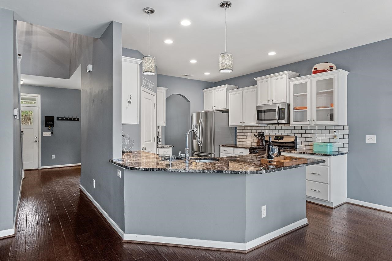 2929 Britmass Drive Raleigh, NC 27616 - Photo 8 of 35 a kitchen with kitchen island granite countertop a sink cabinets and wooden floor