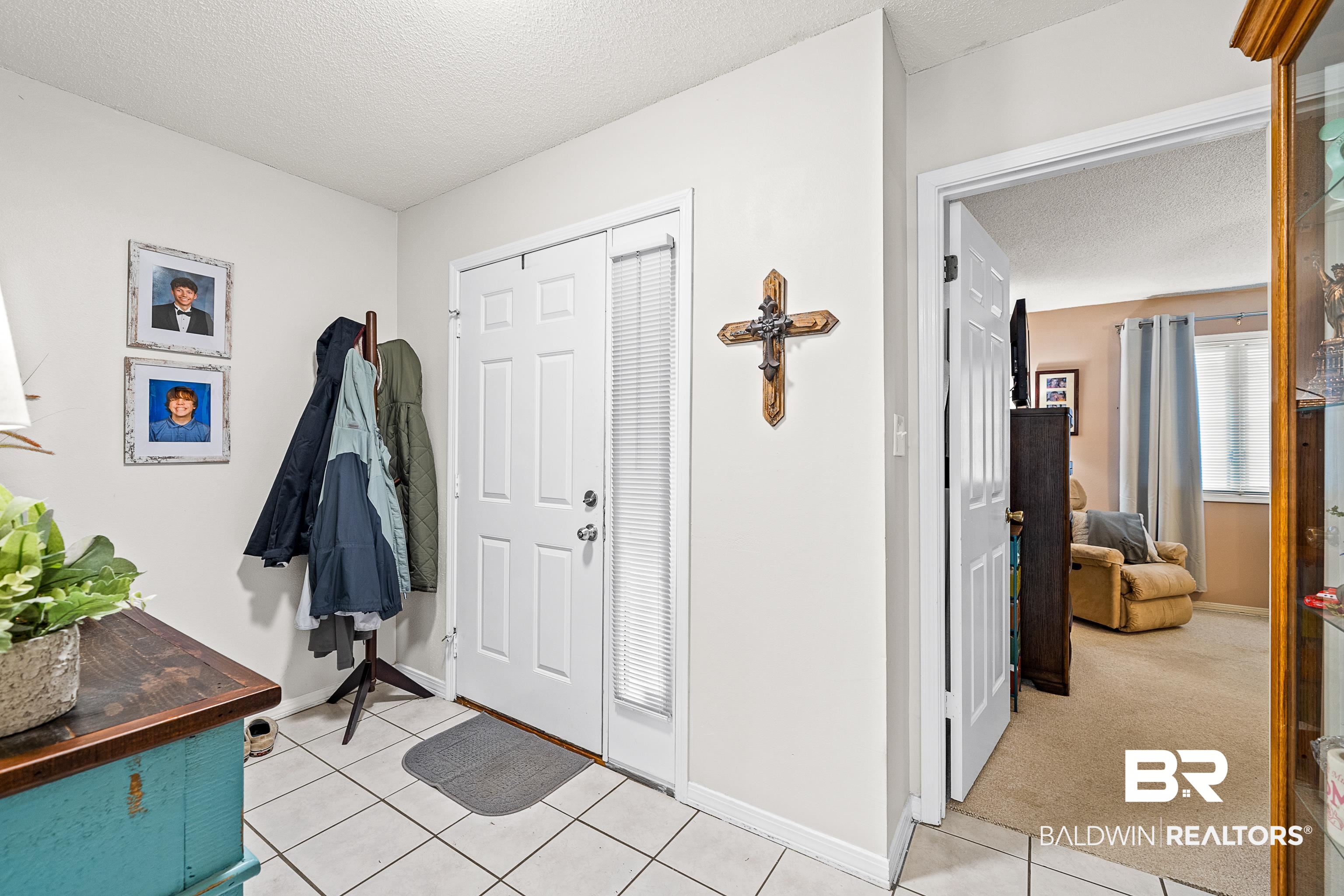 1701 Regency Road, Unit 106 Gulf Shores, AL 36542 - Photo 2 of 42 Entryway featuring a textured ceiling, light tile patterned flooring, and light carpet