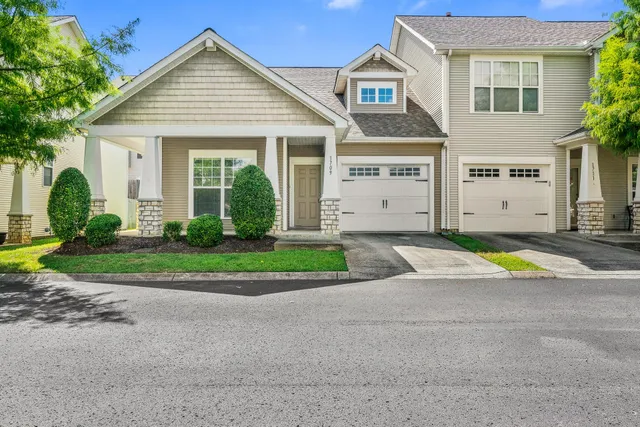 a view of a white house with a small yard and plants