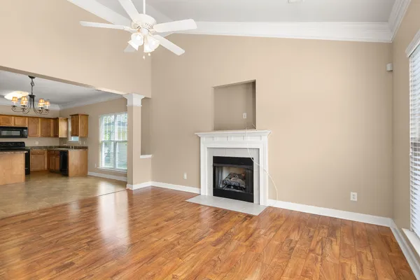 a view of an empty room with wooden floor and a fireplace